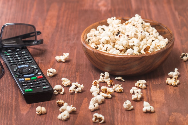 Popcorn, remote control and 3D glasses on wooden background